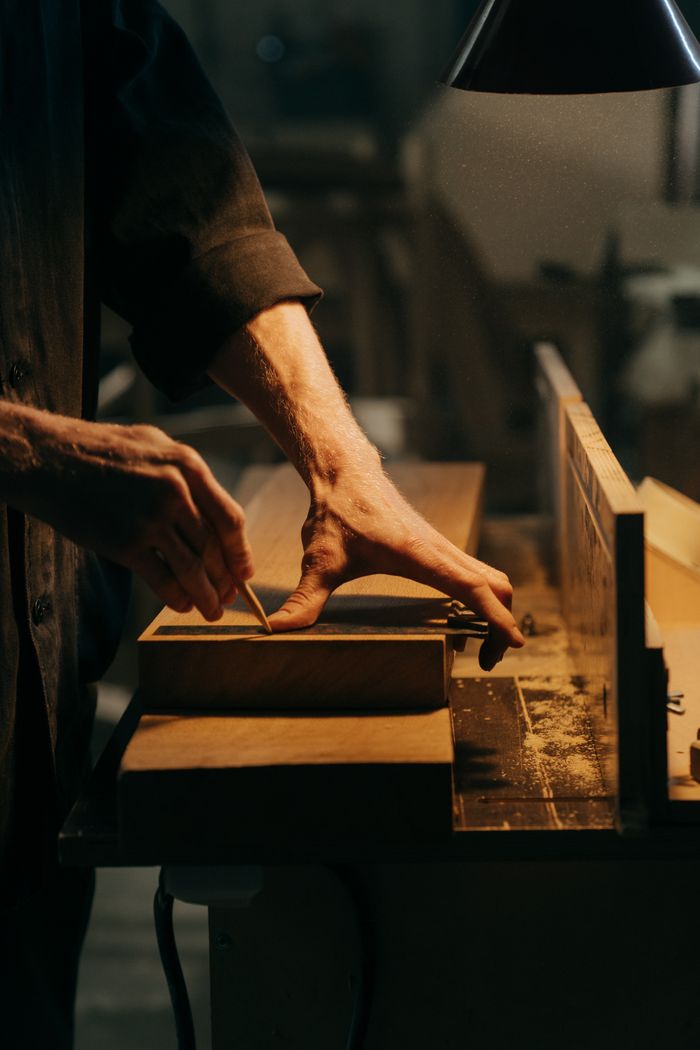 Mastering the First Impression: Your intriguing post title goes here A craftsman skillfully sanding a wooden plank in a well-lit workshop.